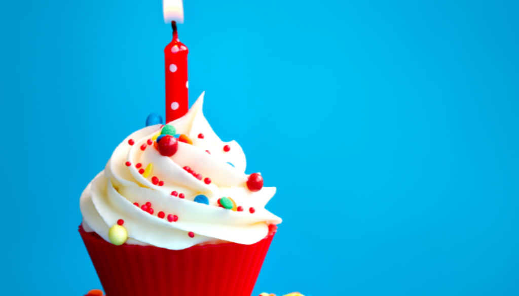 single cupcake with one burning candle on a blue background